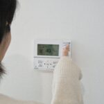 給湯器のパネルを操作する女性